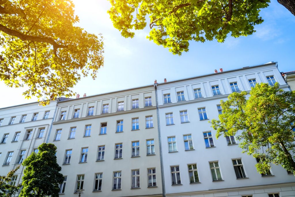 Vor Altbauten stehen mehrere Bäume, was sehr einladend und angenehm erscheint.