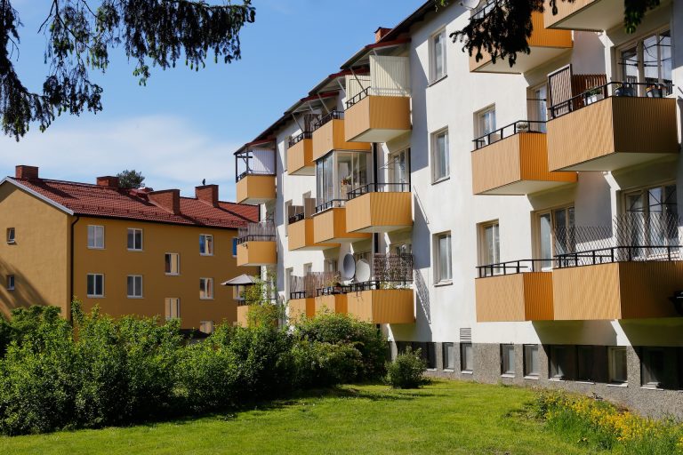 Mehrfamilienhäuser mit Balkonen in einer grünen Wohnanlage.