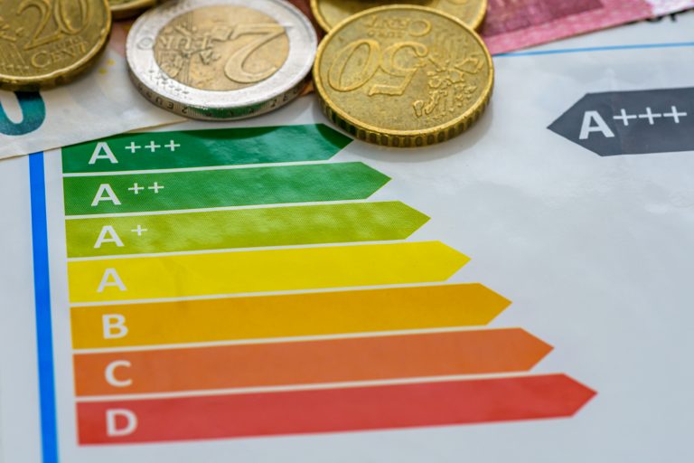 Energieeffizienzklassen auf einem Etikett neben Münzen und Banknoten.